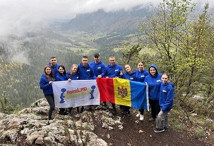 Echipa HamaL.MD pe vârf de munte, cu drapelul Moldovei și steagul companiei